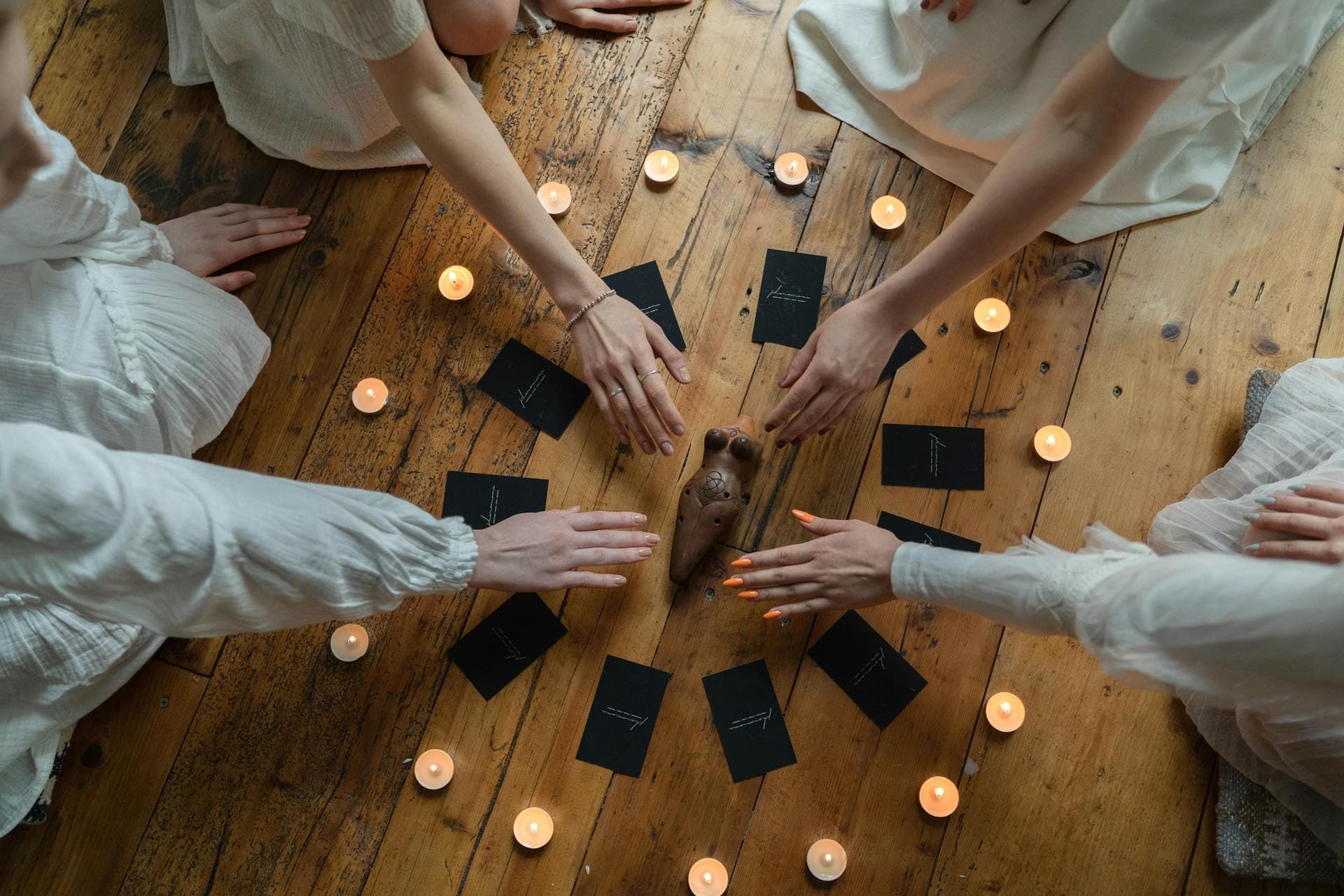A group of people in a circle with candles and cards on the floor